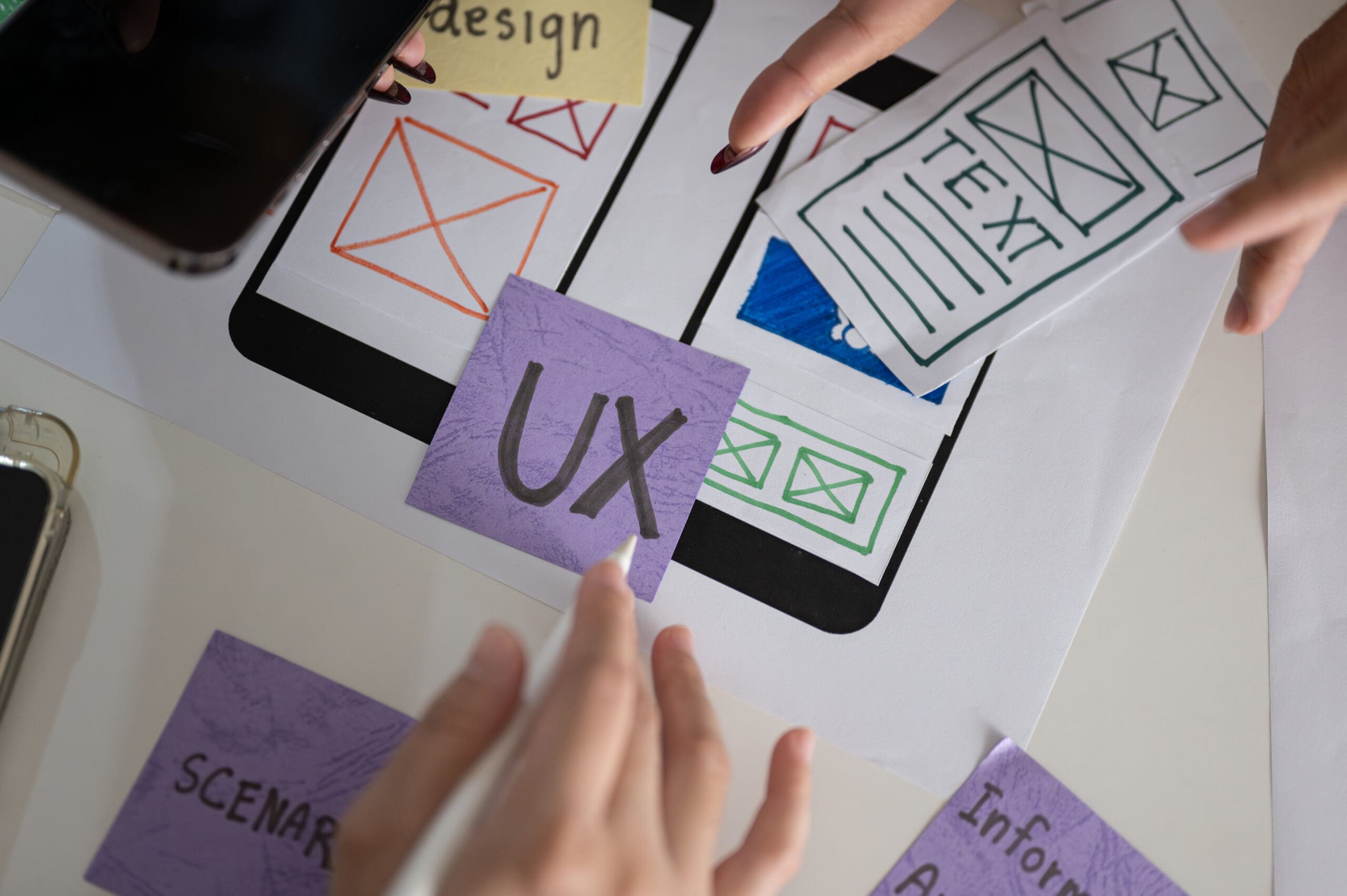 Fingers pointing at a purple paper with the word ux on it