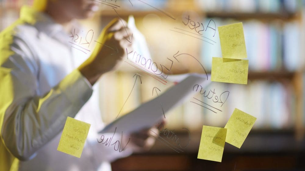 Image depicting an office worker doing an agile project with sticky notes on a plastic board